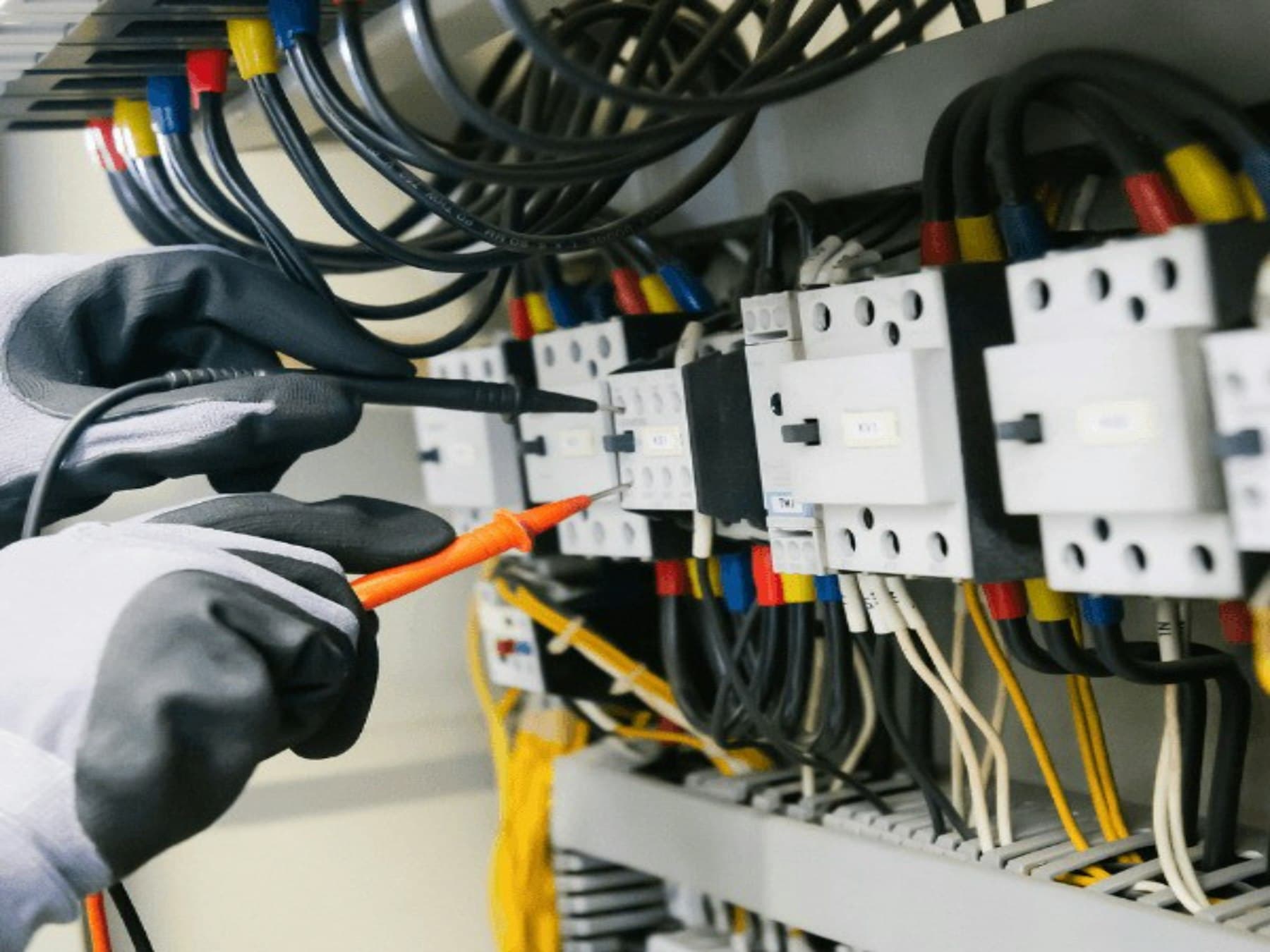 Eletricista testando painel elétrico com multímetro.
