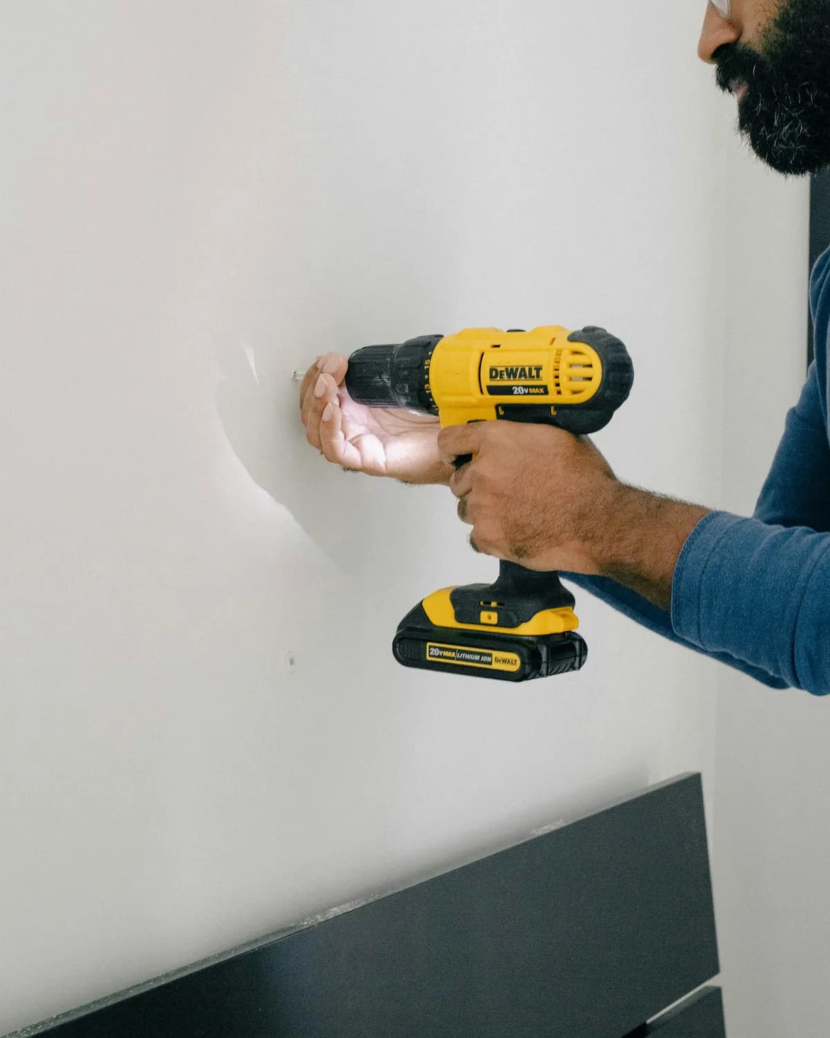 Profissional furando parede para fixação durante instalação residencial.